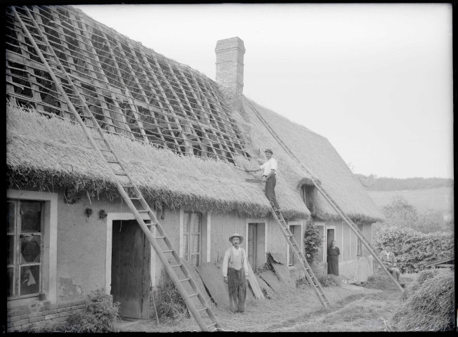 Ouvriers travaillant à la réalisation d'un toit de chaume d'une chaumière.