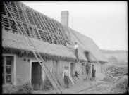 Ouvriers travaillant à la réalisation d'un toit de chaume d'une chaumière.
