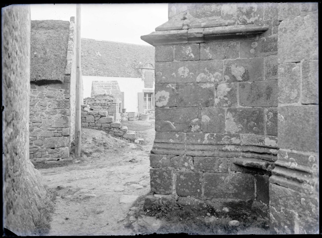 Vue sur une ferme en pierre depuis l'angle d'une église de Bretagne.
