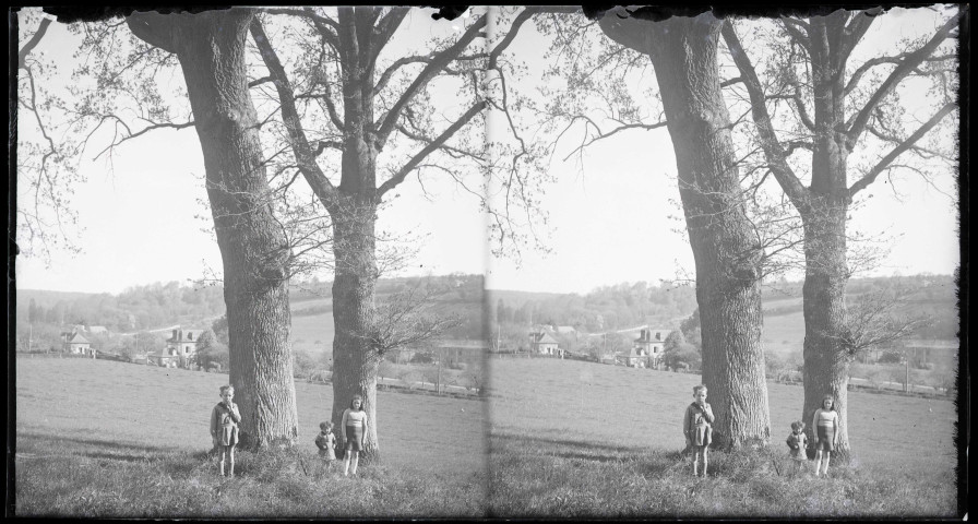 Jeunes enfants posant entre deux chênes dans la campagne aux alentours du presbytère de l'abbé Bretocq à Rosay-sur-Lieure (Eure).