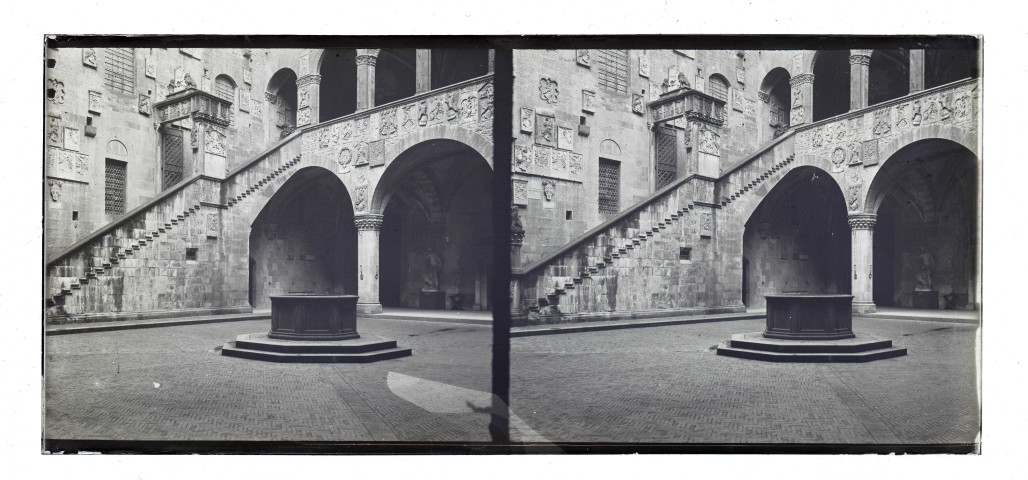 Cour intérieure ornementée avec balcon, puits et statues.