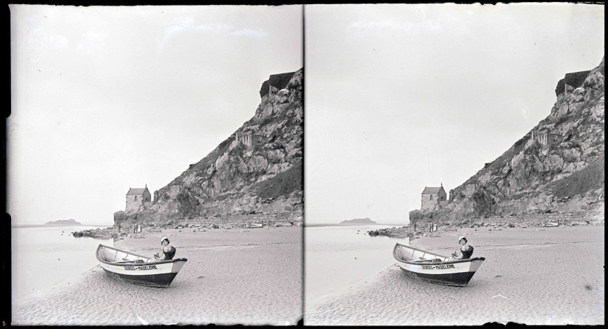 Femme à bord d'une barque échouée sur le sable près de la chapelle Saint-Aubert au Mont-Saint-Michel (Manche).