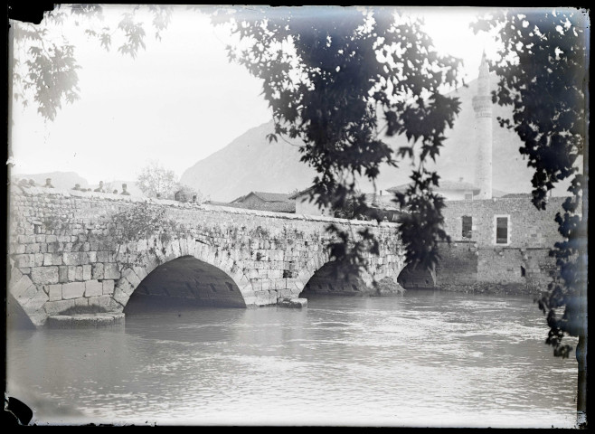 Pont en pierre traversant un fleuve et minaret.