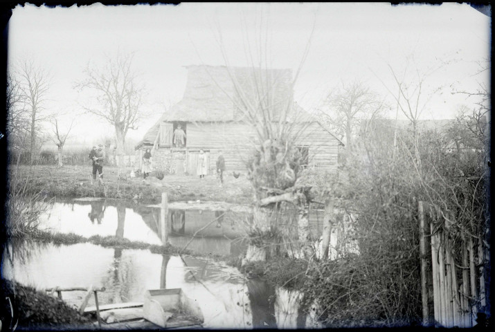 Famille de paysans devant le point d'eau d'une cour de ferme.