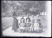 Melle Bonjean avec un groupe d'enfants dans un jardin.