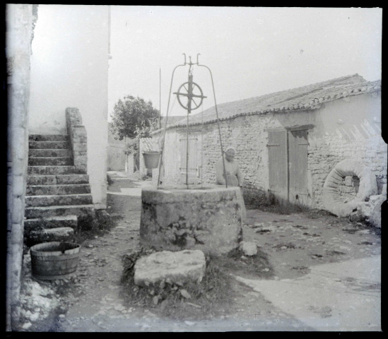 Vieille femme accoudée à la margelle d'un puits.