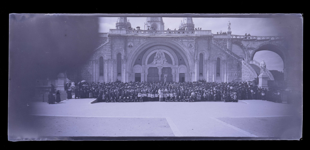Pèlerins et ecclésiastiques sur l'esplanade de la basilique de Lourdes (Hautes-Pyrénées).