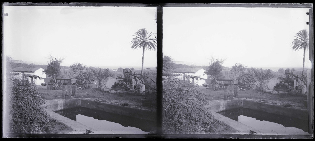 Noria et bassin dans le jardin d'une habitation.