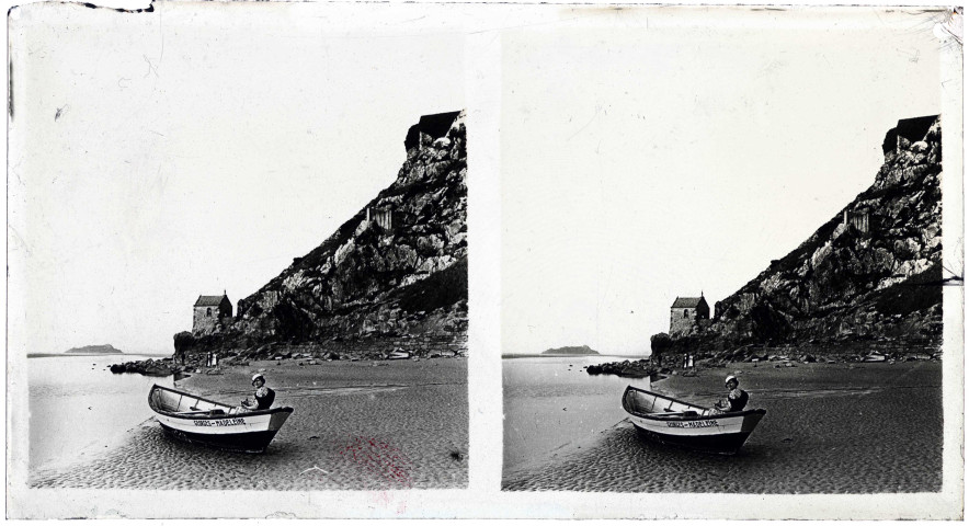 Femme à bord d'une barque échouée sur le sable près de la chapelle Saint-Aubert au Mont-Saint-Michel (Manche).