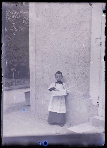 Enfant de chœur devant le mur d'un bâtiment.
