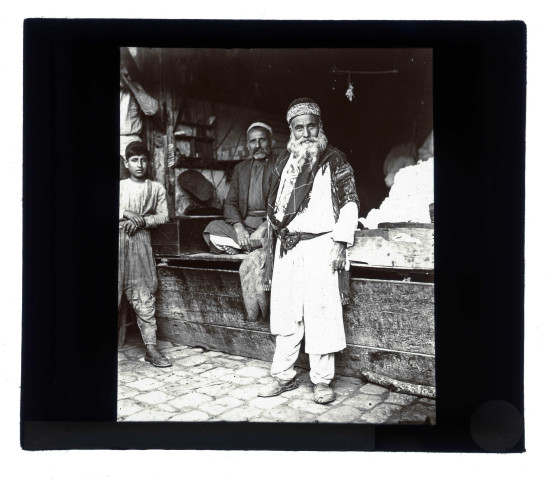 Homme en costume traditionnel devant une échoppe.
