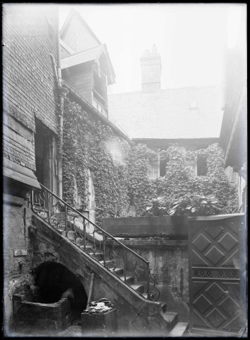 Arrière-cour avec puits et escalier de pierre d'une maison à pans de bois de Lisieux (Calvados).