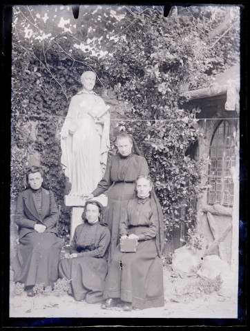 Femmes dans un jardin au pied de la statue d'un saint.