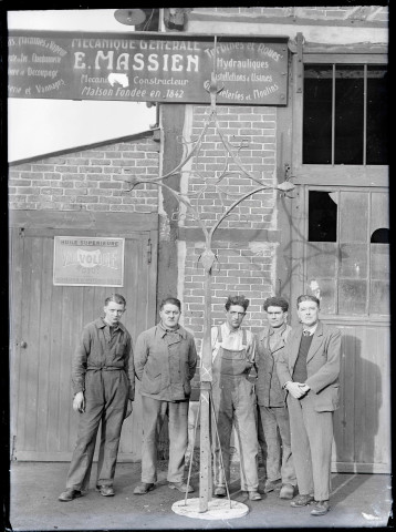 Ouvriers posant avec la croix de la flèche de l'église de Ménesqueville (Eure) posée au sol.
