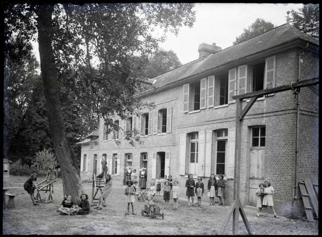 Enfants et sœurs à cornettes dans la cour d'une école de campagne.