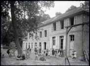 Enfants et sœurs à cornettes dans la cour d'une école de campagne.