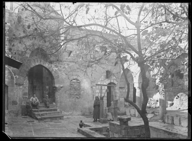Femme et enfants dans une cour auprès d'un puits.