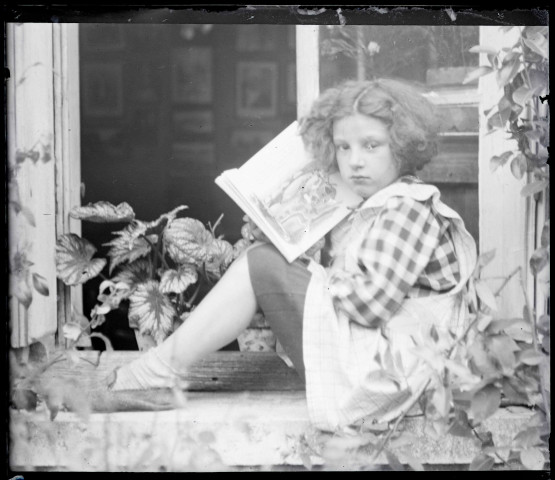 Portrait d'une petite fille lisant assise sur un appui de fenêtre. (famille Bretocq).