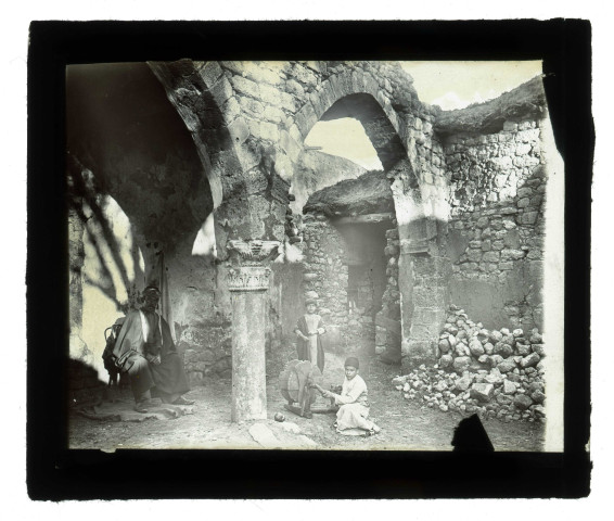 Homme et des jeunes enfants dans des ruines et vestiges (arcades, chapiteaux).