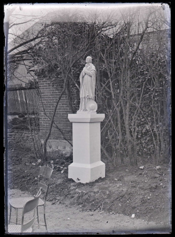 Statue d'un saint dans un jardin, probablement Saint-Jérôme.
