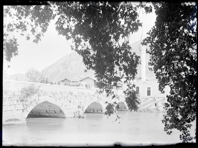 Pont en pierre traversant un fleuve et minaret.