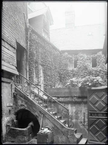 Arrière-cour avec puits et escalier de pierre d'une maison à pans de bois de Lisieux (Calvados).