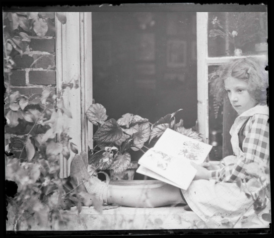 Portrait d'une petite fille lisant assise sur un appuie de fenêtre. (famille Bretocq).