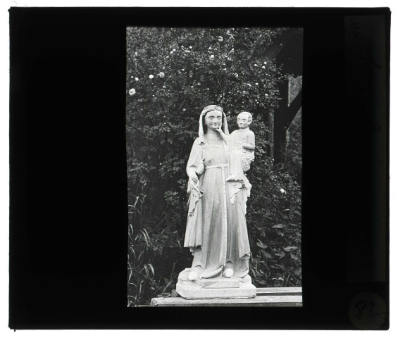 Église de Saint-Jean-du-Thenney (Eure), Vierge à l'enfant posée dans un jardin.