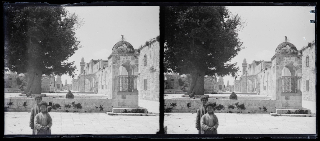 Enfants sur une place de village, à l'arrière plan un minaret.