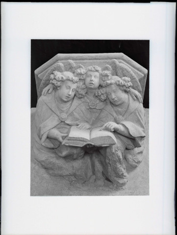 Groupe sculpté de trois anges lisant un livre, détail du culot sous la statue de la Vierge de l'Annonciation du XIVe siècle de l'église d'Écouis (Eure)
