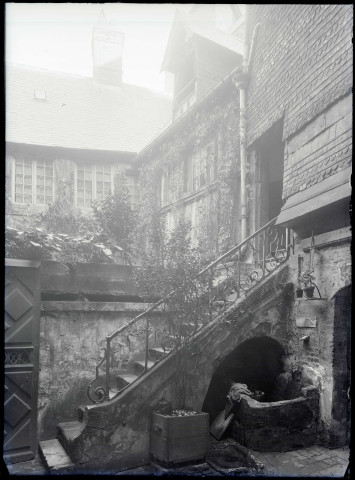 Arrière cour avec puits et escalier de pierre d'une maison à pans de bois de Lisieux (Calvados).