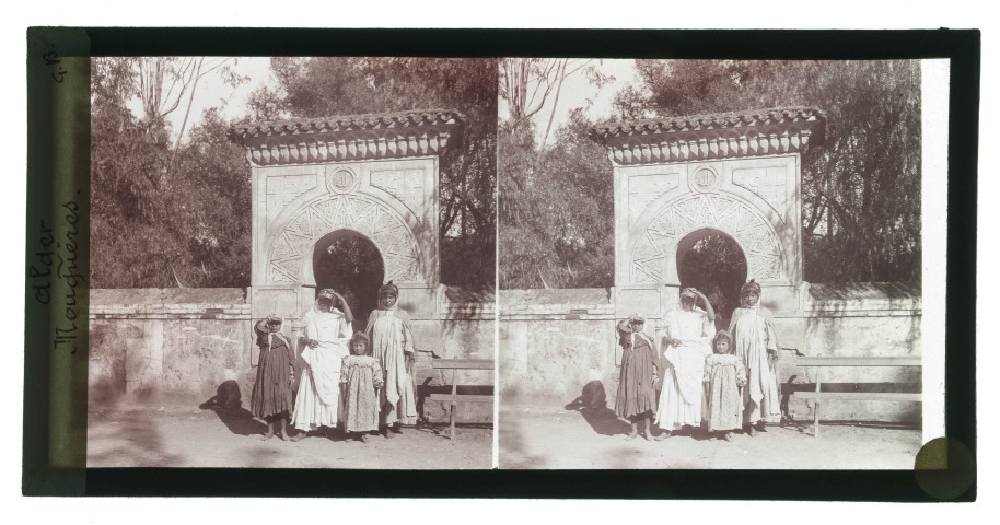 Mouquères devant la porte ornementée d'un jardin public d'Alger (Algérie).
