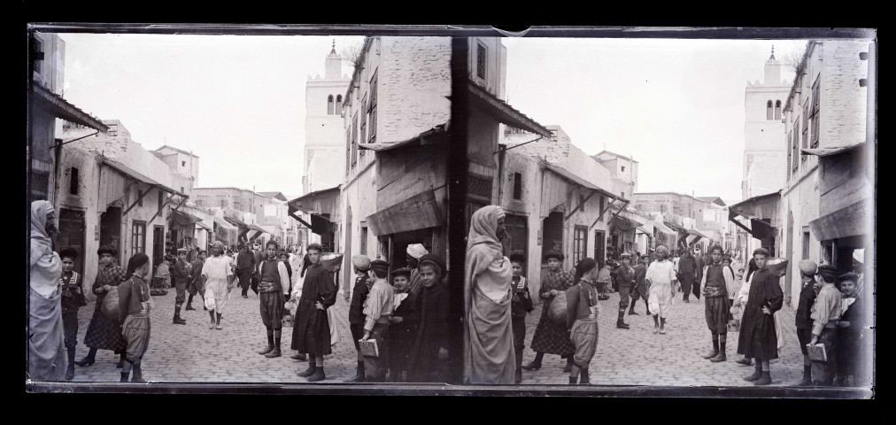 Rue pavée d'un souk avec un minaret en arrière-plan.
