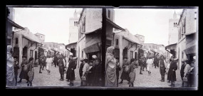 Rue pavée d'un souk avec un minaret en arrière-plan.