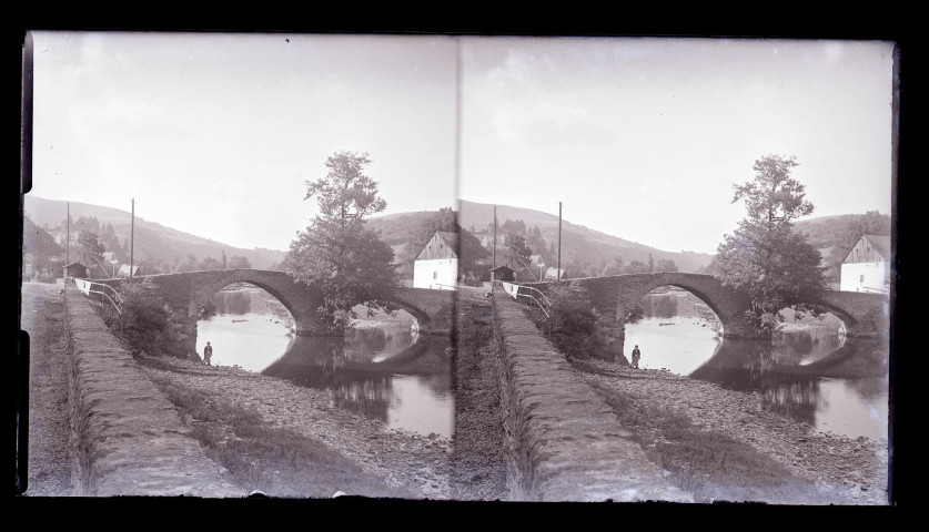 Pont de pierre à arcades surplombant une rivière traversant la campagne du Luxembourg.