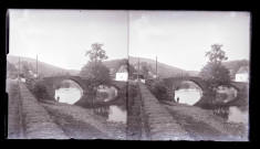 Pont de pierre à arcades surplombant une rivière traversant la campagne du Luxembourg.