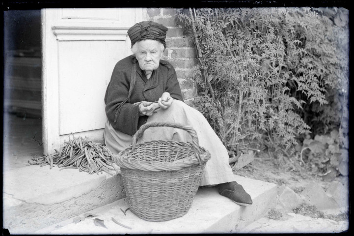 La mère de l'abbé Gabriel Bretocq épluchant des haricots verts sur le perron du presbytère de Rosay-sur-Lieure (Eure).