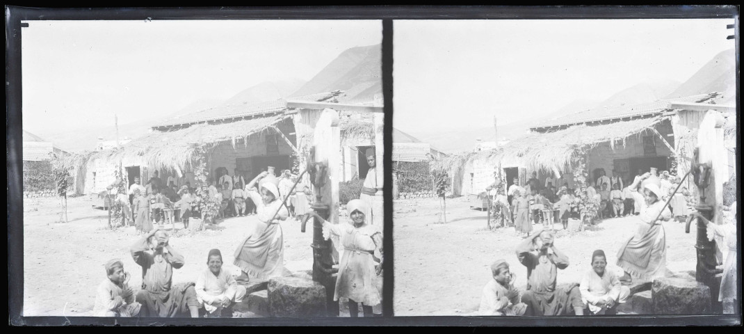 Femmes et enfants à la fontaine devant la terrasse d'un café.