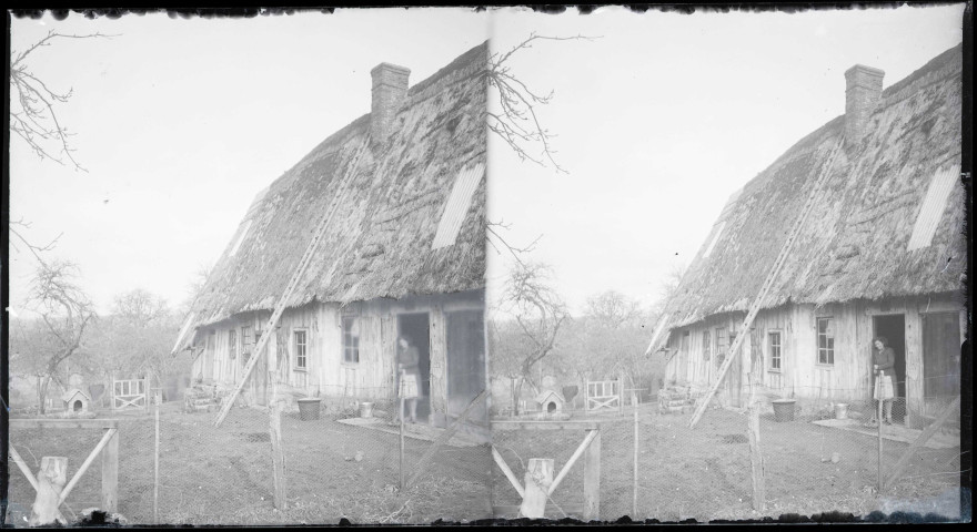 Femme posant à la porte d'une chaumière normande.