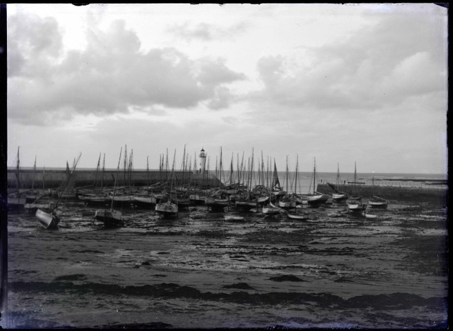 Chaloupes dans un port breton devant une jetée et son phare.
