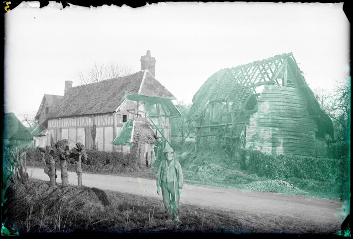 Paysan devant une chaumière normande et sa grange en ruines.