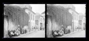 Enfants et probablement leurs maîtresses assis devant le porche d'une habitation ou d'une école.