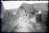 Jeune fille assise sur la margelle d'un puits d'une maison normande.