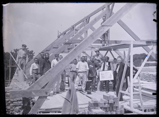 Groupe d'ouvriers sous une charpente en construction.