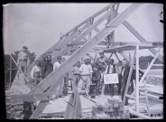 Groupe d'ouvriers sous une charpente en construction.