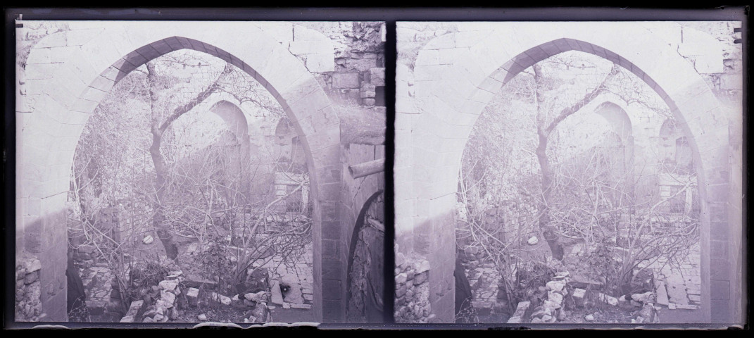Ruines et amas de pierres d'édifices sous des arcades.