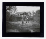 Enfants dans une cour de ferme au bord d'une rivière avec les maisons sur pilotis.