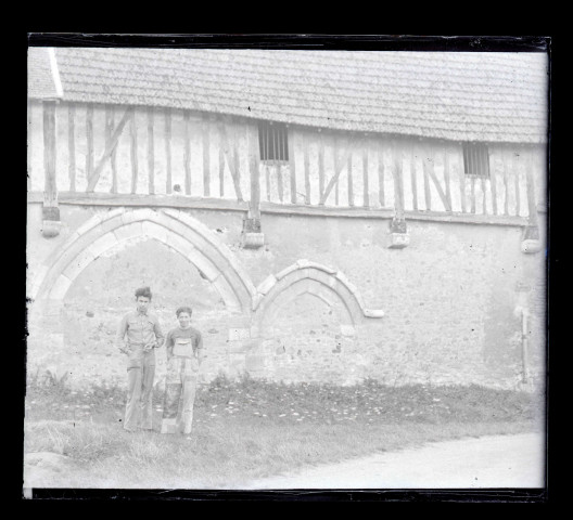 Deux ouvriers posant devant les anciennes arcatures d'un manoir normand.