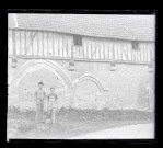 Deux ouvriers posant devant les anciennes arcatures d'un manoir normand.