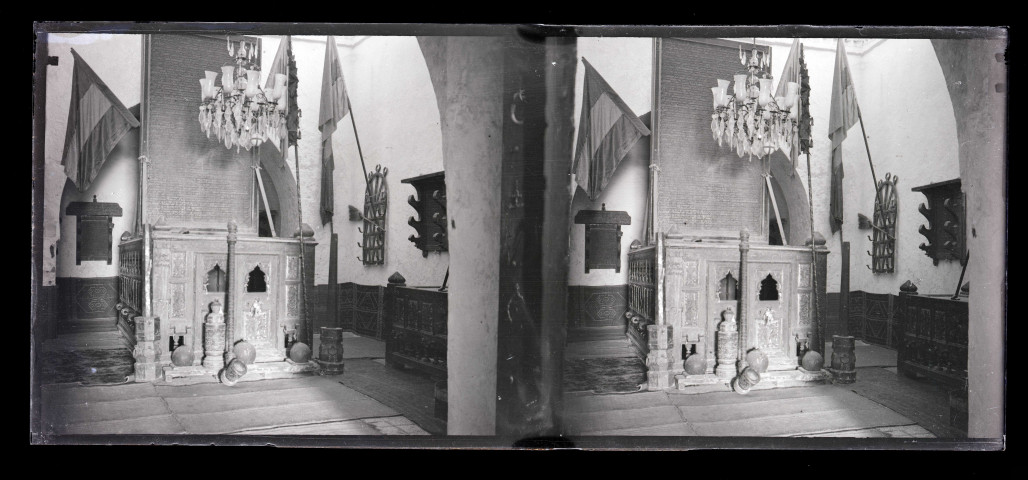 Intérieur d'un édifice (meuble en bois ornementé, drapeaux).